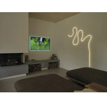 Salon moderne avec ruban lumineux courbé au mur, téléviseur, cheminée et banc bas en béton avec bois de chauffage.