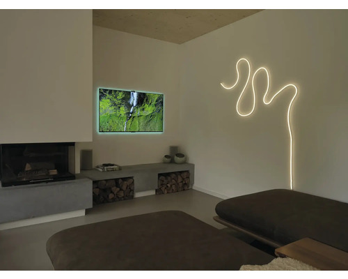 Salon moderne avec ruban lumineux courbé au mur, téléviseur, cheminée et banc bas en béton avec bois de chauffage.