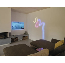 Salon moderne avec cheminée, télévision et un ruban LED mural courbé aspect néon au-dessus d'un canapé.