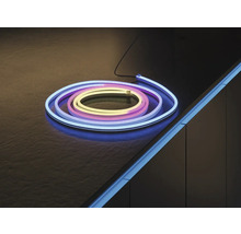 Ruban LED néon flexible, enroulé sur une surface sombre et monté comme éclairage d'accentuation sur le bord d'un meuble.