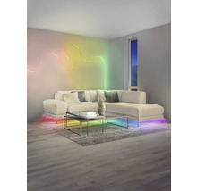 Salon moderne avec ruban LED ondulé au mur, canapé d'angle éclairé et table basse sur un tapis.