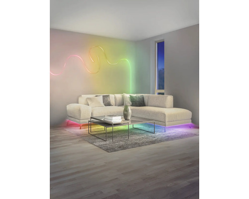 Salon moderne avec ruban LED ondulé au mur, canapé d'angle éclairé et table basse sur un tapis.