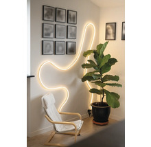 Pièce lumineuse avec un ruban LED flexible au mur, un fauteuil et une grande plante d'intérieur en pot.