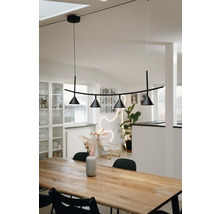 Suspension moderne noire avec quatre spots coniques au-dessus d une table à manger en bois massif dans une pièce lumineuse de style scandinave.