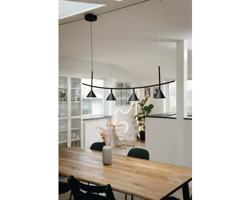 Suspension moderne noire avec quatre spots coniques au-dessus d une table à manger en bois massif dans une pièce lumineuse de style scandinave.
