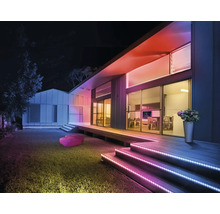 Façade de maison moderne de nuit avec des bandes LED colorées sur les escaliers et le toit pour un éclairage extérieur d ambiance.