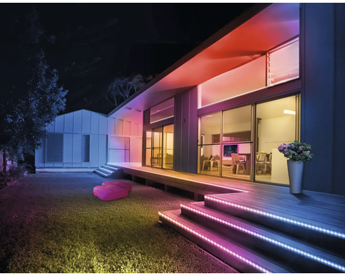 Façade de maison moderne de nuit avec des bandes LED colorées sur les escaliers et le toit pour un éclairage extérieur d ambiance.