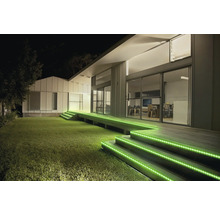 Éclairage extérieur d une terrasse moderne de nuit avec des rubans LED verts sur les marches en bois.