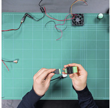 Mains connectant un câble à un module SSR ADDON sur un plan de travail avec des composants électroniques tels qu'un ventilateur et des câbles.