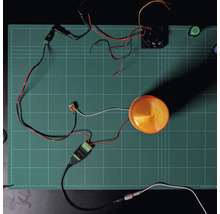 Module Shelly Solid State Relay Addon avec feu à éclats et ventilateur connectés sur un tapis de découpe pour démonstration du câblage.