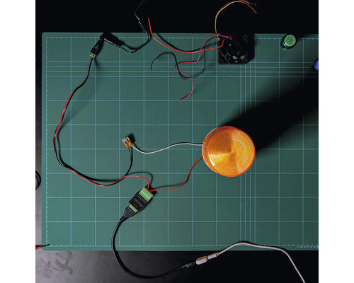 Module Shelly Solid State Relay Addon avec feu à éclats et ventilateur connectés sur un tapis de découpe pour démonstration du câblage.