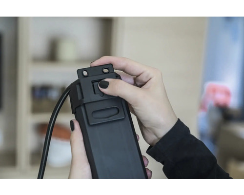 Eine Person bedient einen schwarzen Kabelkanal.