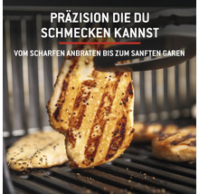 Des filets de poulet grillés sur une grille sont retournés avec une pince de barbecue.
