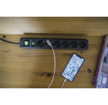 Mehrfachsteckdose mit Überspannungsschutz und einem angeschlossenen Smartphone