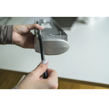 Une personne tient un store et un cordon dans sa main.