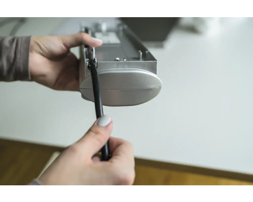 Une personne tient un store et un cordon dans sa main.