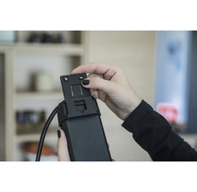 Une personne fixe un support sur un moteur de volet roulant.