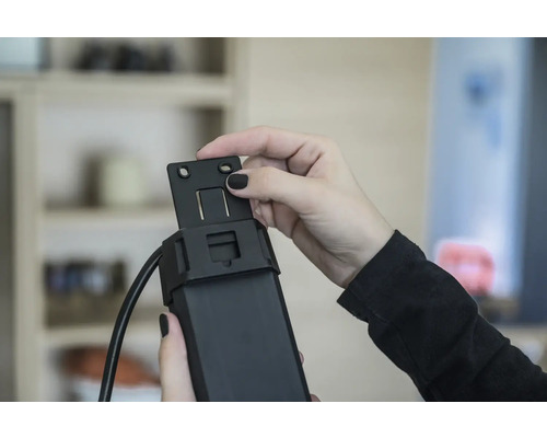 Une personne fixe un support sur un moteur de volet roulant.