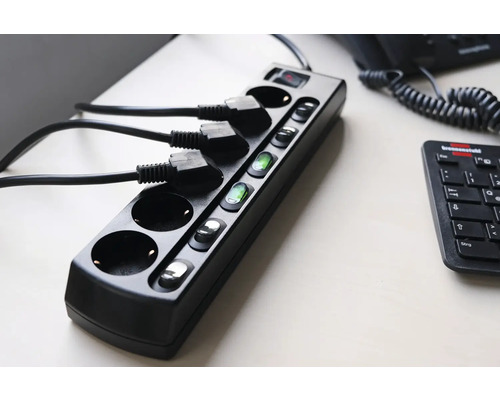 Multiprise noire avec interrupteurs et câbles branchés sur une table