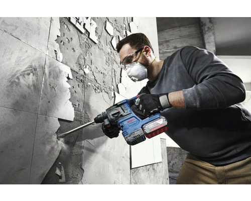 Un homme retire des carreaux avec un marteau perforateur Bosch.