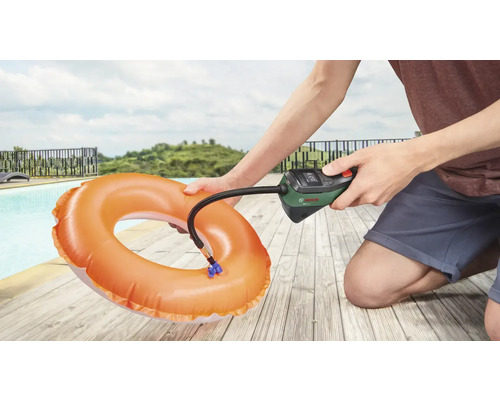 Une personne gonfle une bouée avec une pompe à air Bosch à côté d'une piscine.