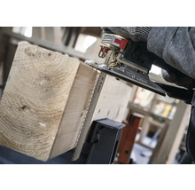 Une scie sauteuse coupe une planche de bois.