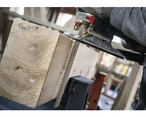 Une scie sauteuse coupe une planche de bois.