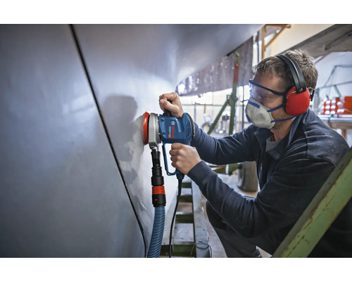 Un artisan utilise une ponceuse excentrique pour poncer une surface.