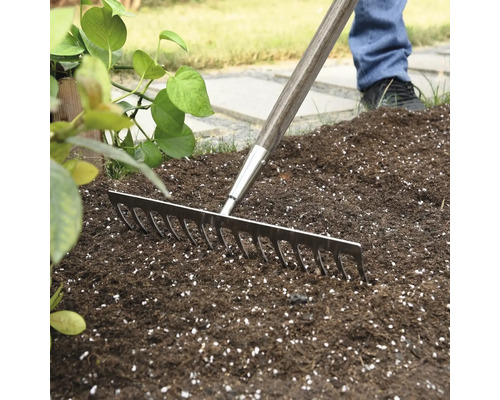Gartenrechen mit Holzgriff im Einsatz auf Gartenerde.