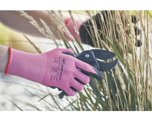 Une personne coupe de l'herbe avec un sécateur et porte des gants de jardinage.