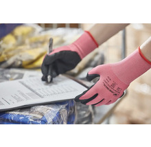 Des mains portant des gants de travail écrivent sur un document