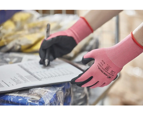 Des mains portant des gants de travail écrivent sur un document
