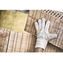 Ein Arbeiter trägt mit Handschuhen Ziegelsteine.