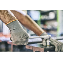 Une personne porte des gants de protection et utilise une clé à molette.