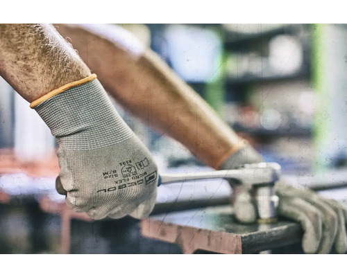 Une personne porte des gants de protection et utilise une clé à molette.