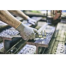 Une personne mesure une pièce métallique avec un pied à coulisse numérique sur un support.