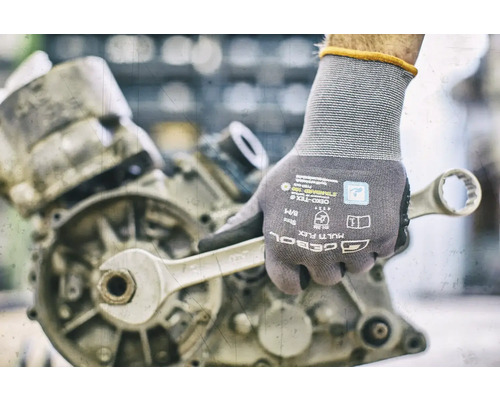 Main avec gant de travail et clé sur un moteur