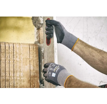 Homme portant des gants de travail et un niveau à bulle lors de travaux de rénovation.