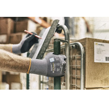 Une personne portant des gants de travail pousse un chariot roulant.