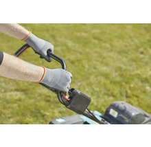 Une personne utilise une tondeuse à gazon avec des gants de travail.