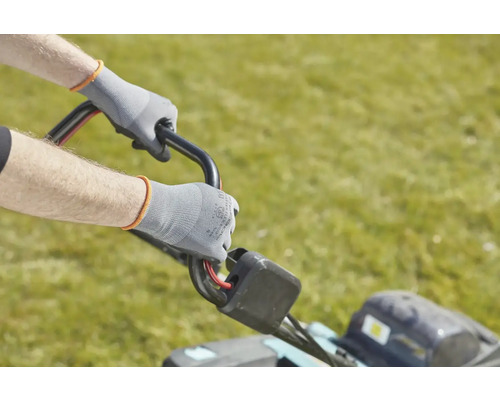 Une personne utilise une tondeuse à gazon avec des gants de travail.