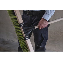 Une personne tient un balai vert avec un manche en bois.