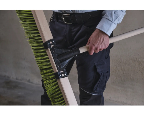 Une personne tient un balai vert avec un manche en bois.