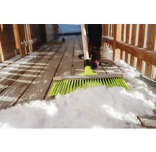 Déneigement avec un balai sur une terrasse en bois