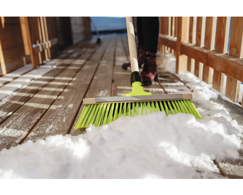 Déneigement avec un balai sur une terrasse en bois