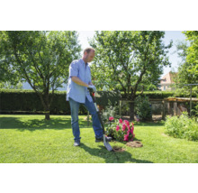Mann pflanzt Blumen mit einem Spaten im Garten.