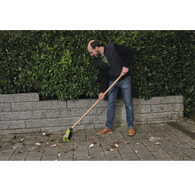 Une personne balaie les feuilles avec un balai de rue.