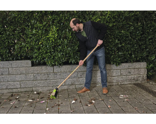 Une personne balaie les feuilles avec un balai de rue.