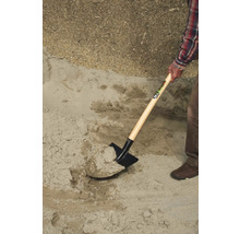 Une personne pelle du sable avec une bêche.