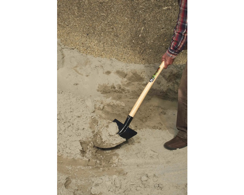 Une personne pelle du sable avec une bêche.